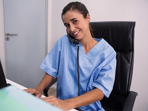 Woman at dental reception desk answering phone