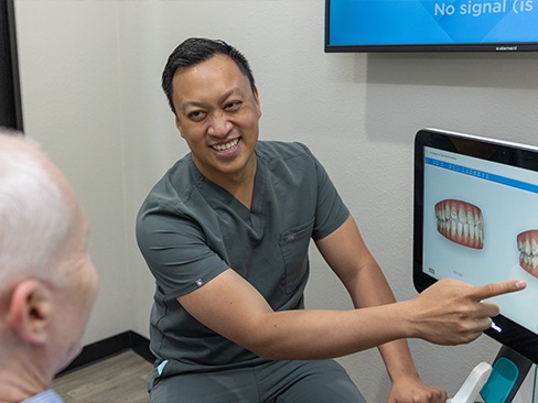 Woman in dental chair holding cheek during emergency dentistry visit