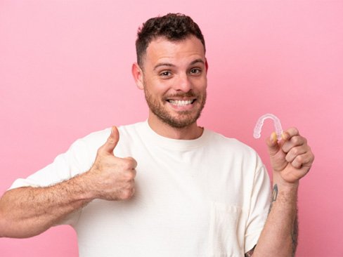 Adult man giving thumbs up for his Invisalign treatment