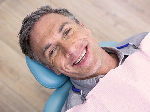 Smiling man in dental chair for dental checkup and teeth cleaning