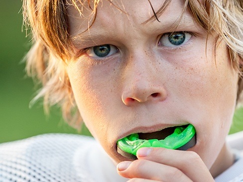 Teen placing athletic mouthguard