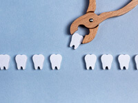 one toy tooth being pulled with toy wooden forceps from a row