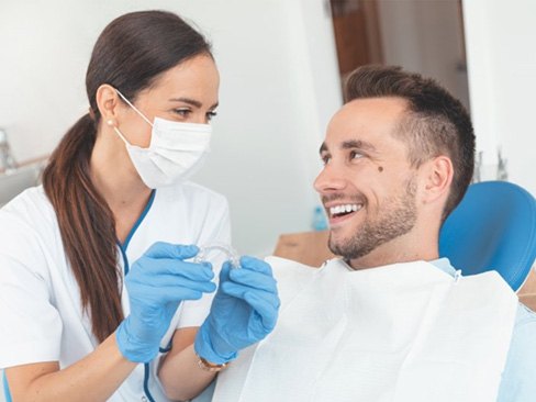 man talking to his Invisalign dentist in Dallas Factors That Affect the Cost of Invisalign