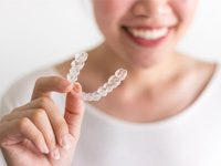 smiling person holding an Invisalign aligner 
    Invisalign vs. Smile Direct Club™
    