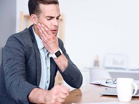 Man with a dental emergency in Dallas holding his mouth