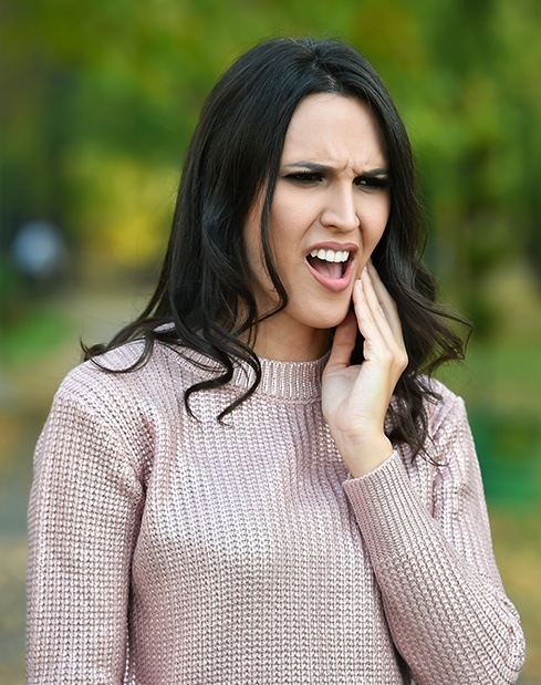 Woman in pain holding jaw before tooth extractions