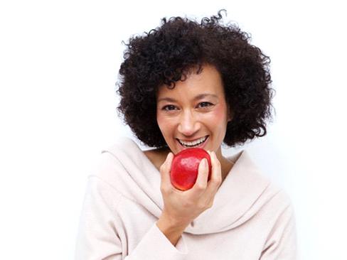woman with dental implants in Dallas biting into a red apple