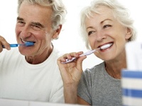 senior man and woman brushing their teeth