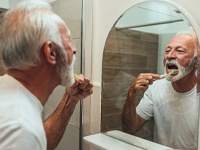 mature man brushing teeth for dental implants in Dallas