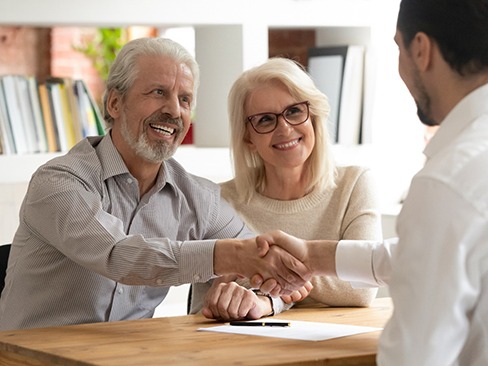 Older couple learning about treatment from implant dentist in Dallas