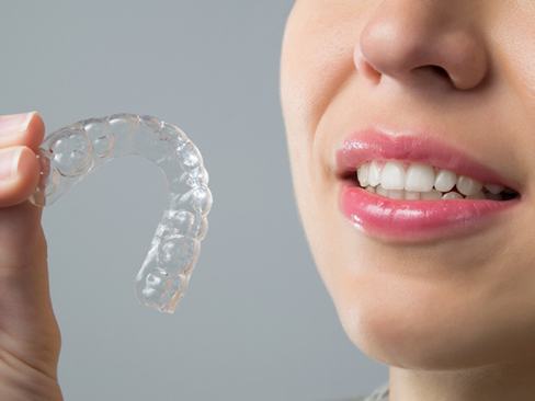 A woman holding an Invisalign aligner