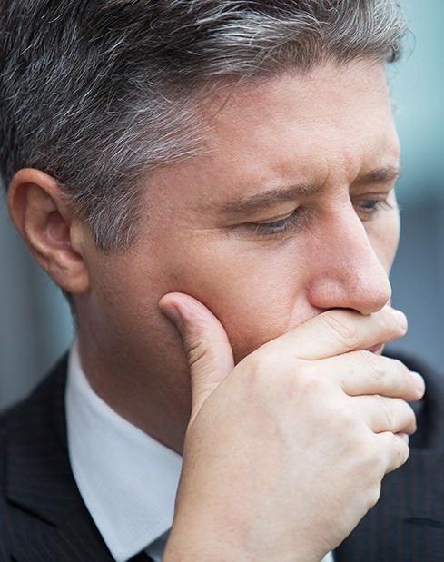 Man with missing teeth covering his mouth