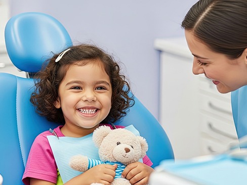 Little girl smiling and holding a teddy bear