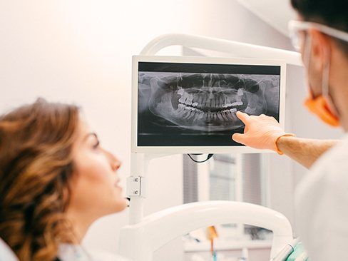 Dentist and patient looking at digital dental x-rays