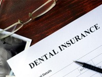 Dental insurance lying on desk with X-rays and glasses
