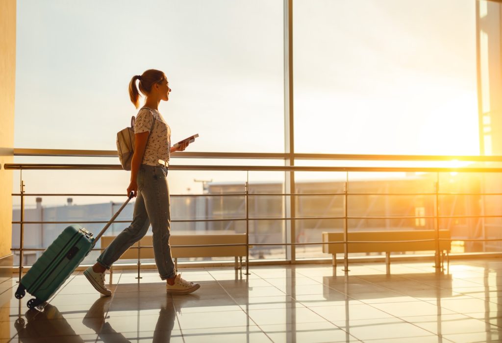 Young woman walking through airport with suitcase