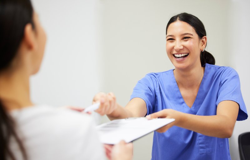 A dental worker handing forms to a patient 