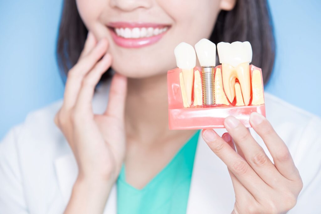 Nose-to-chest view of dentist holding sample implant and touching her cheek