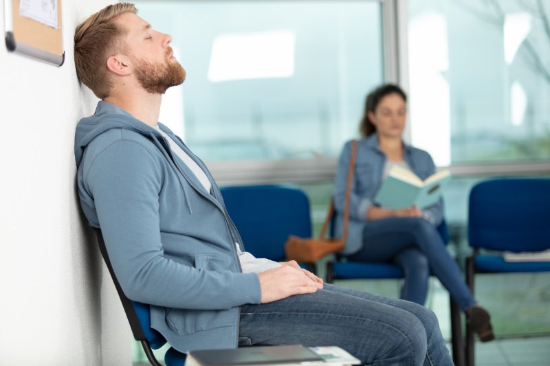 A man closing his eyes while sitting in a doctor’s waiting room